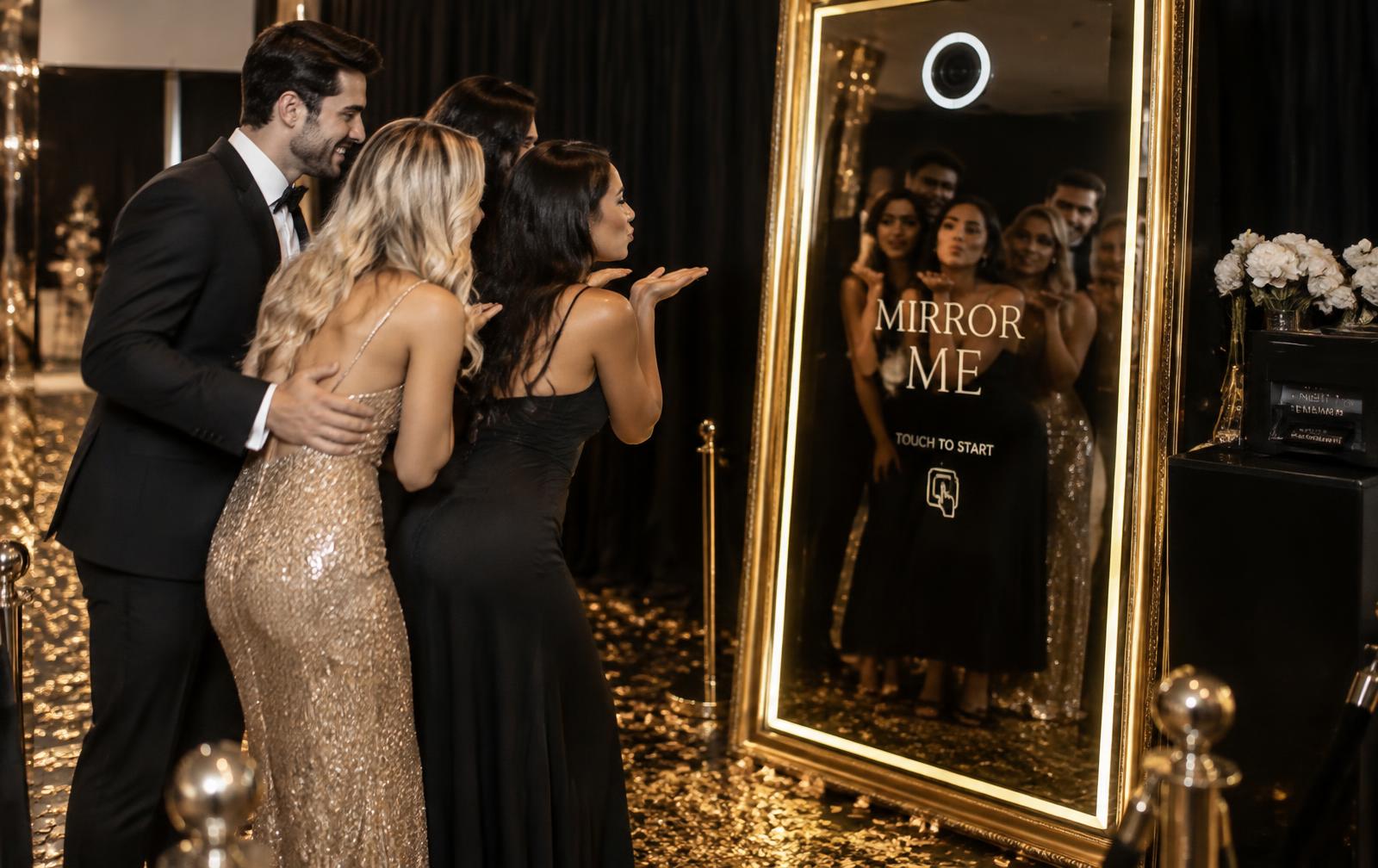 Guests posing in front of a gold framed Mirror Me photobooth